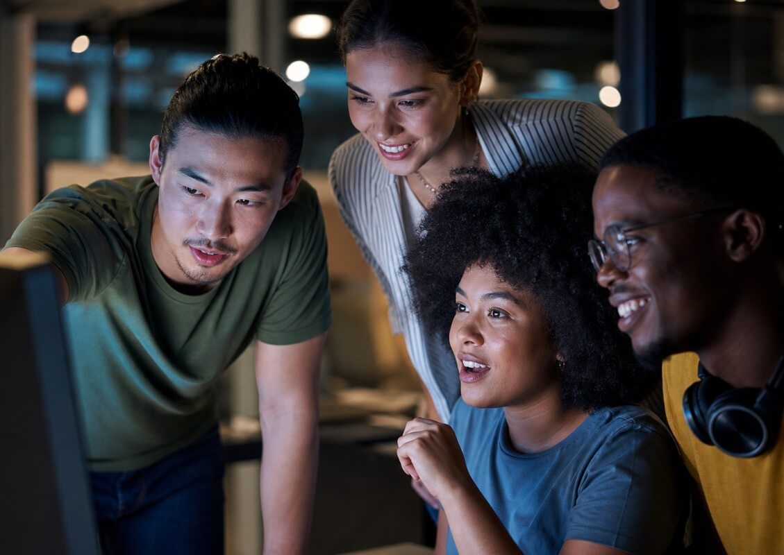 students working together on a laptop in a dark, focused environment