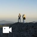 A couple stands atop a mountain